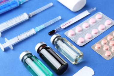 Eczacı konsepti. Mavi arka planda şişeler, şırıngalar ve haplar, yakın plan.