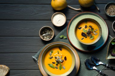 Gri ahşap masada servis edilen lezzetli balkabağı çorbası.