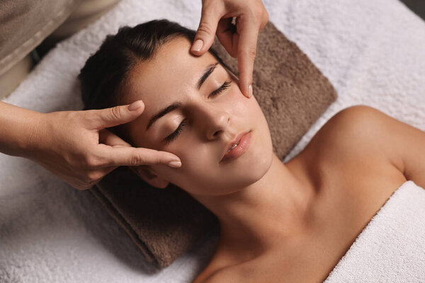 Привлекательная женщина наслаждается массажем лица, над видом. Процедура красоты