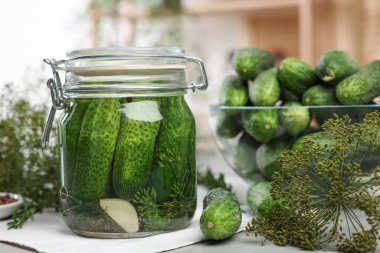 Kavanozda salatalık turşusu, dereotu ve taze olanlar masada, yakın plan.