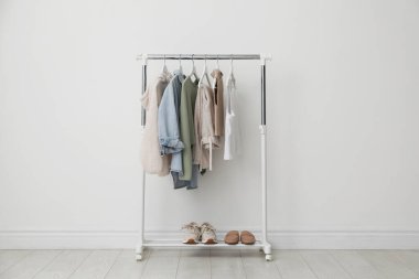 Beyaz duvarın yanında giysi ve ayakkabılarla dizilin.