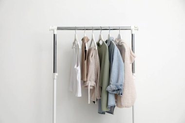 Beyaz duvarın yanında farklı kıyafetlerle dizilin.