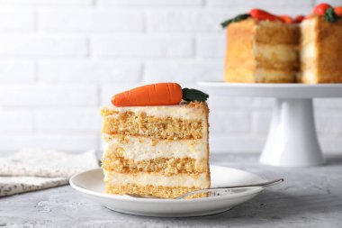 Tabak dolusu lezzetli havuçlu kek, gri desenli masa, yakın plan.