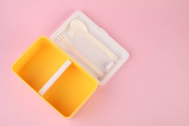 Açık pembe arka planda çatal bıçak takımı olan plastik beslenme çantası.