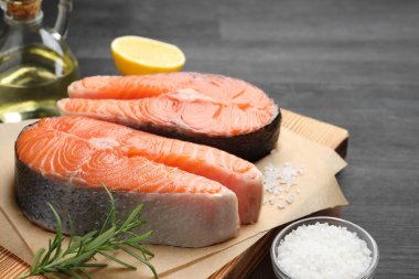 Siyah masada taze çiğ somon biftekleri ve baharatlar, yakın plan.