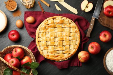 Lezzetli ev yapımı elmalı turta ve koyu dokulu masa malzemeleriyle düz bir kompozisyon.
