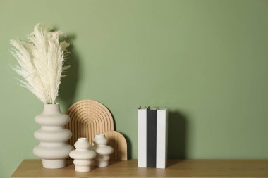 Güzel dekoratif bitkiler, vazolar, ahşap tahtalar ve içinde yeşil duvarın yanındaki masada farklı şehirlerin isimlerinin yazılı olduğu ciltli kitaplar.