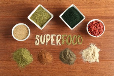 Superfood kelimesi ve ahşap masa üzerindeki farklı sağlıklı tozlar.