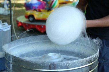 Man making cotton candy with machine outdoors, closeup
