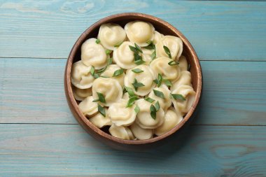 Lezzetli pelmeni, yeşil soğanlı açık mavi ahşap masa, üst manzara.