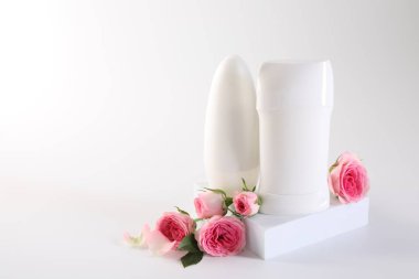 Farklı deodorantlar beyaz arkaplanda güzel gül çiçekleri, metin için boşluk