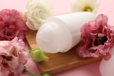 Pembe arka planda deodorant ve güzel Eustoma çiçekleri, yakın plan.