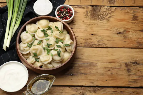 Tahta masada servis edilen yeşil soğanlı leziz pelmeni. Metin için boşluk