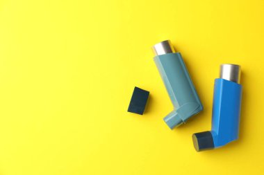 Asthma inhaler on yellow background, top view. Space for text clipart