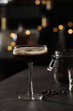 Lezzetli espresso martini ve kahve çekirdekleri ile koyu renkli masada bulanık ışıklara karşı.