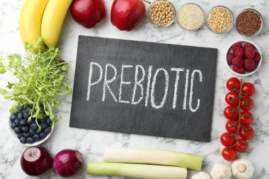 Tahtada Prebiyotik ve beyaz mermer masa üzerinde farklı ürünler var.