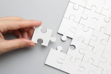 Açık gri arka planda beyaz bulmacayı çözen kadın, üst görünüm