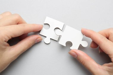 Açık gri arka planda beyaz bulmacayı çözen kadın, üst görünüm