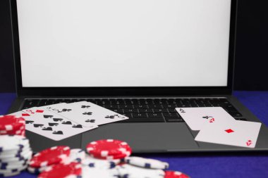 Laptop, poker fişleri ve mavi masada iskambil kağıtları, yakın plan. Çevrimiçi oyun