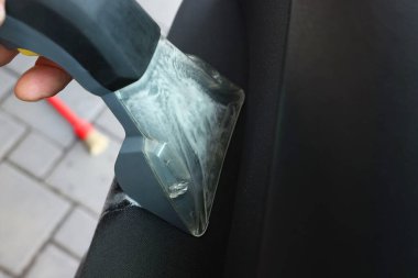 Arabanın kapısını elektrikli süpürgeyle temizleyen adam, yakın plan.