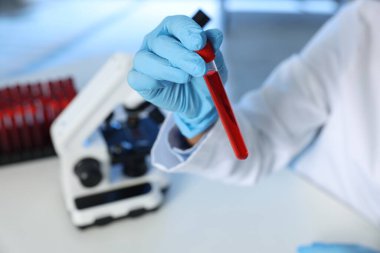 Laboratuvar testi. Doktor, kan örneğiyle birlikte test tüpünü kapalı bir masada tutuyor.