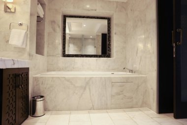 Lüks bir otelde mermer küveti ve aynası olan şık bir banyo.