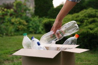 Geri dönüşüm konsepti. Dışarıdaki karton kutuya plastik şişe koyan adam.