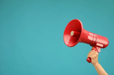 Mavi arka planda megafon hoparlörü tutan kadın, yakın plan. Metin için boşluk