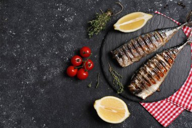 Lezzetli ızgara uskumru, kekik, limon ve domatesler koyu dokulu masa, düz yatak. Metin için boşluk