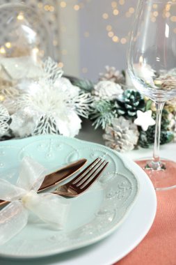 Masada tabak, çatal bıçak ve şenlik dekoru olan bir Noel yeri.