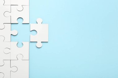 Açık mavi arka planda beyaz yapboz parçaları, üst manzara. Metin için boşluk