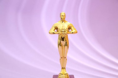 One golden Oscar award on violet background clipart