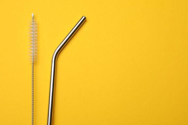 Metal pipetler ve sarı arka planda temizlik fırçası. Metin için boşluk
