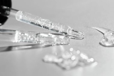 Gri arkaplanda kozmetik serumu ve pipetler, yakın plan.