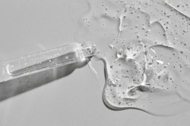 Gri arkaplandaki pipetten akan kozmetik serumu, üst görünüm