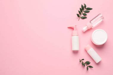 Farklı kozmetik ürünleri ve pembe arka planda yapraklar. Metin için boşluk