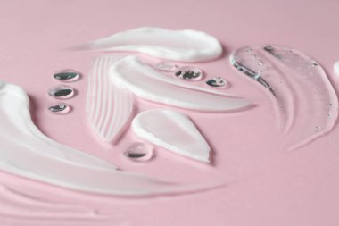 Pembe arka planda farklı kozmetik ürünlerinin kokusu, yakın plan