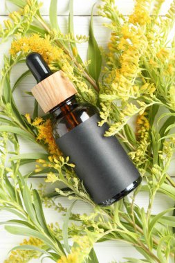 Bottle of tincture and goldenrods flowers on white wooden table, flat lay clipart