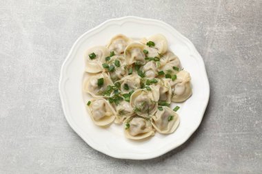 Lezzetli pelmeni yeşil soğanlı ve dereotlu gri desenli masa, üst manzara.