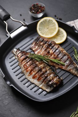 Lezzetli ızgara uskumru, biberiye ve limon tencerede koyu dokulu masa.