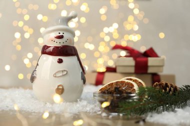 Masadaki bulanık ışıklara karşı komik kardan adam figürü ve diğer dekorlar