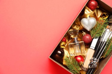 Makyaj fırçaları, kozmetik ürünler, parfüm ve Noel süslemeleri mercan arka planda, üst manzara. Metin için boşluk