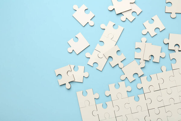White puzzle pieces on light blue background, top view