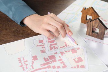 Ev araması. Ahşap masada haritaları ve ev figürleri olan kadın, yakın plan.