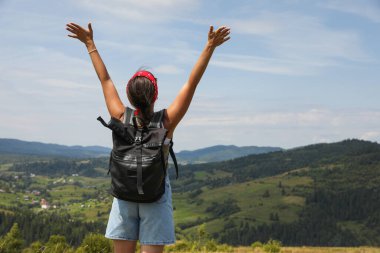 Sırt çantalı turist, geniş kolları ve arka manzarası olan manzaranın tadını çıkarıyor. Metin için boşluk