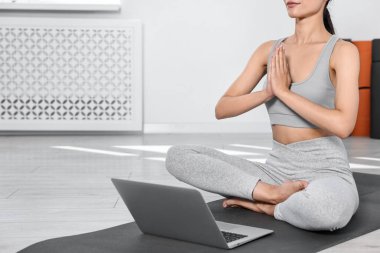 Evde yoga minderinin üzerinde meditasyon yapan bir kadın, yakın plan. Metin için boşluk