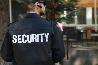 Dışarıda üniformalı ve güneş gözlüklü bir güvenlik görevlisi var.
