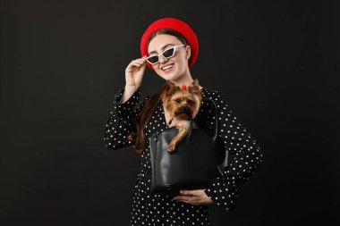 Siyah arka planda Yorkshire Terrier köpeği olan güneş gözlüklü bir kadın.