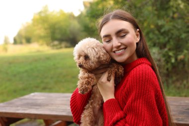 Sonbahar parkında sevimli köpeğiyle gülümseyen bir kadın. Metin için boşluk