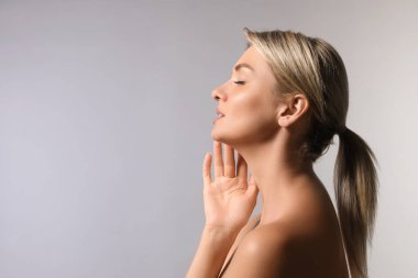 Kozmetoloji. Gri arka planda mükemmel cilde sahip güzel bir kadın, metin için boşluk